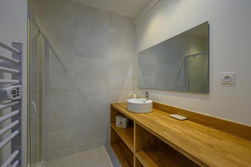La salle de bains est pourvue d'un lavabo, d'un miroir et d'une douche. dans l'établissement LA P'TITE VANNETAISE - Petite maison au bord de l'eau à Conleau avec vélos, à Vannes