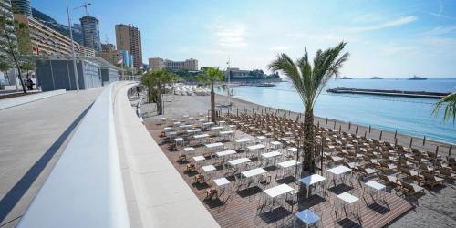 plaża z kilkoma stołami i krzesłami obok wody w obiekcie Mari stunning apartment next to Monaco with a sea view terrace w mieście Beausoleil