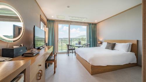 una camera d'albergo con letto, scrivania e finestra di J View Hotel a Seogwipo