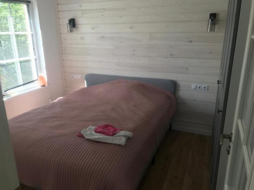 a small bedroom with a bed with a pink blanket at Cozy holiday house with sauna and entertainment in Puskelniai
