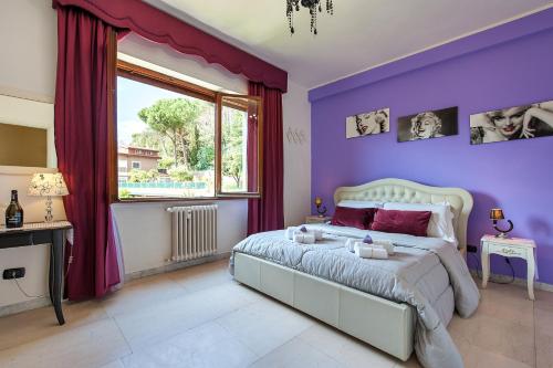ローマにあるL'Oasi Verde a San Pietro apartmentの紫色のベッドルーム(ベッド1台、窓付)
