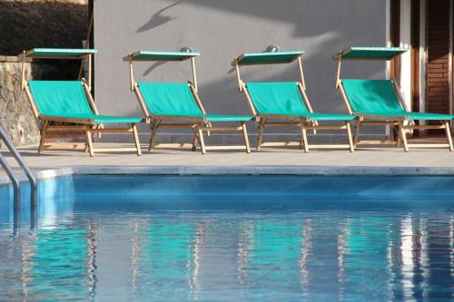 four chairs sitting next to a swimming pool at Villa Veralda, la magia di una Toscana insolita in Fivizzano