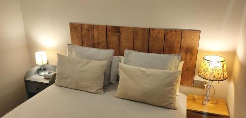 uma cama com almofadas brancas e uma cabeceira em madeira em Acogedor apartamento en Llivia em Llivia