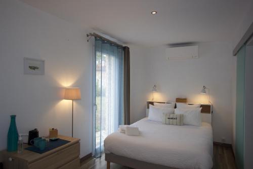 ein Schlafzimmer mit einem weißen Bett und einem großen Fenster in der Unterkunft La Charentine in Échillais