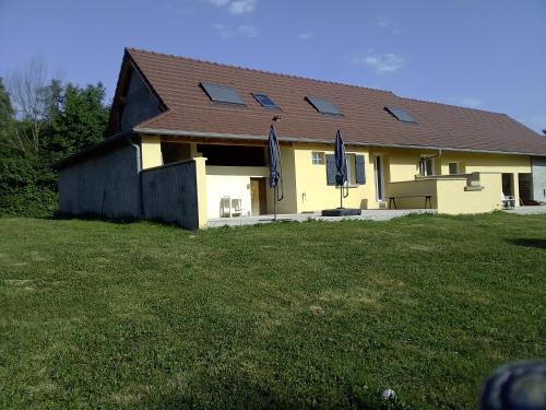 ein gelbes Haus mit einem braunen Dach und einem Grasfeld in der Unterkunft Gîte au bord de la rivière in Frangy-en-Bresse