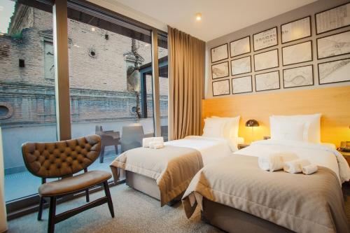 a hotel room with two beds and a chair at Hotel Tuta in Tbilisi City