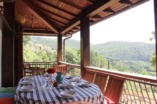 a table on a balcony with a view of the mountains at Villa Veralda, la magia di una Toscana insolita in Fivizzano