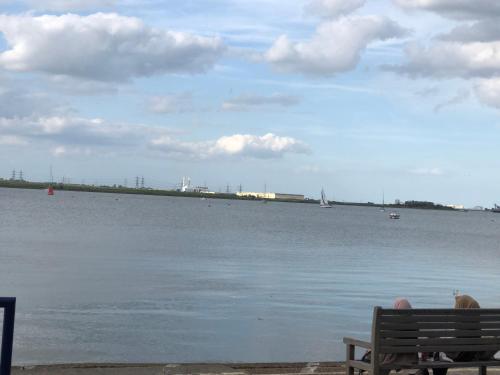 a man sitting on a bench looking at the water at Strand Beach View House in Gillingham