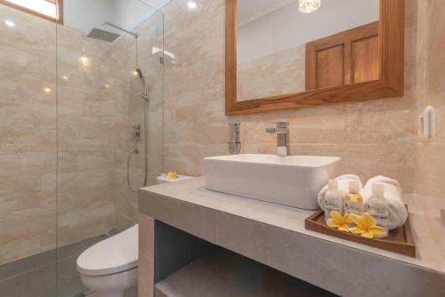 een badkamer met een wastafel, een toilet en een spiegel bij Villa Royal in Singaraja