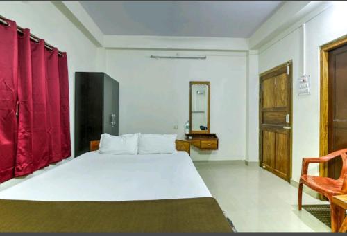 a bedroom with a large white bed with red curtains at Andaman Castle in Port Blair