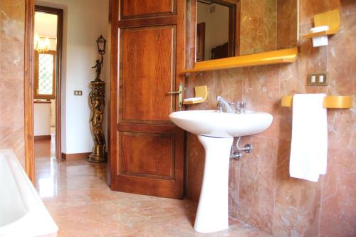 a bathroom with a sink and a wooden door at Villa Veralda, la magia di una Toscana insolita in Fivizzano