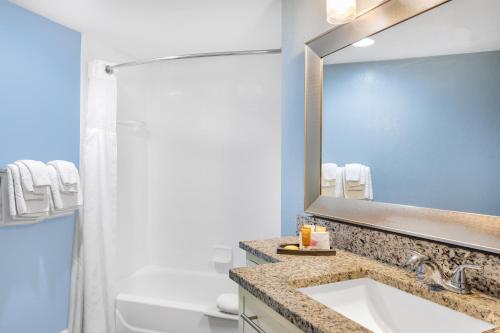 a bathroom with a sink and a mirror at Coconut Palms Beach Resort II a Ramada by Wyndham in New Smyrna Beach