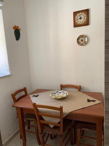 a wooden table with two chairs and a plate on it at Casetta del Maestro in Raffadali