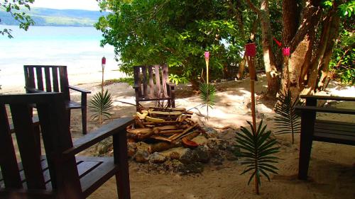 a couple of chairs sitting on a beach at Tranquility Island Eco Dive Resort in Moso Island