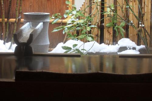 a snow covered table with a statue in front of a fence at Kinosaki Onsen Kawaguchiya Honkan in Toyooka