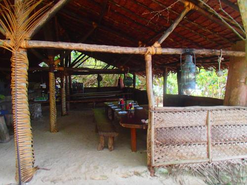 a dining area of a hut with a table and chairs at Tranquility Island Eco Dive Resort in Moso Island