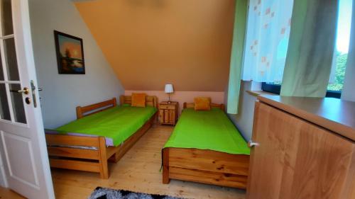 mały pokój z 2 łóżkami i zieloną pościelą w obiekcie Domek do wynajęcia - Siedlisko przy lesie w mieście Rząśnik