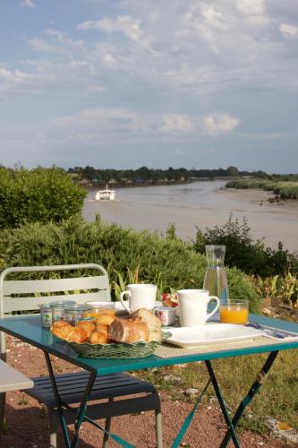 een tafel met een bord brood en kopjes en een rivier bij La Charentine in Échillais