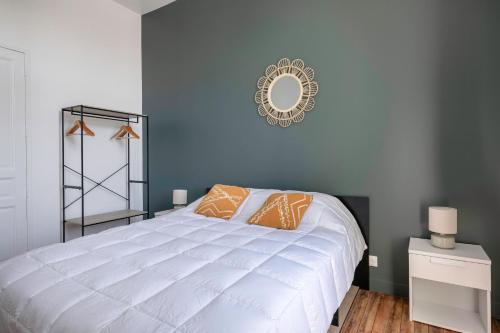 a bedroom with a large white bed and a mirror at Bel appartement vue sur le port du Croisic in Le Croisic