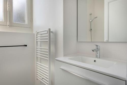 a white bathroom with a sink and a mirror at Bel appartement vue sur le port du Croisic in Le Croisic