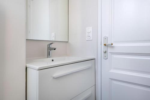 a white bathroom with a sink and a door at Bel appartement vue sur le port du Croisic in Le Croisic