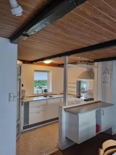 una cucina con banconi bianchi e soffitto in legno di A cozy house to stay in Vandel a Vandel
