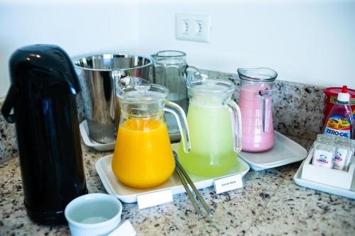 a counter with three glass containers of orange juice at Hotel Vila ÁguaMar in Itapoa