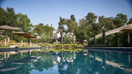 a swimming pool with trees and a house in the background at Domaine Tarbouriech, Hôtel & Spa in Marseillan