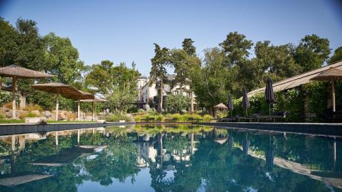 uma piscina com árvores e uma casa ao fundo em Domaine Tarbouriech, Hôtel & Spa em Marseillan