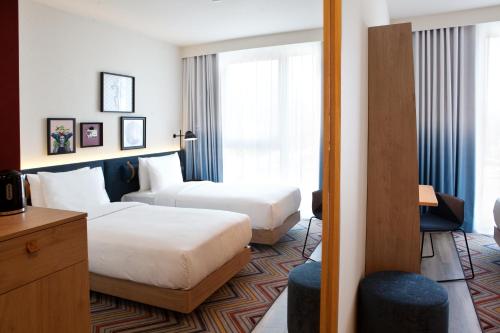 a hotel room with two beds and a window at Hampton By Hilton Regensburg in Regensburg