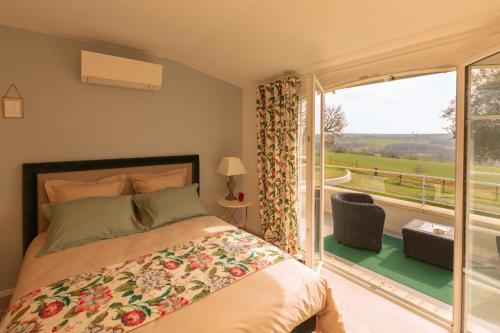 ein Schlafzimmer mit einem Bett und einem großen Fenster in der Unterkunft Chambre d'Hôtes La Courbe in Lugan
