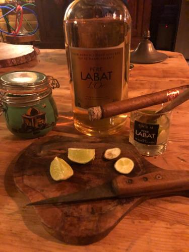 a wooden cutting board with a knife and a bottle of liquor at Le Nid Tropical in Bouillante