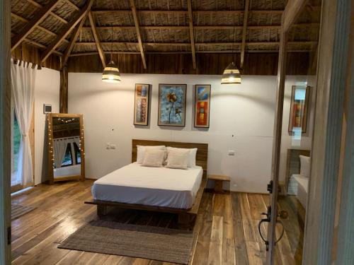 a bedroom with a bed with white sheets and wooden floors at Palmeras del Valle in Santa Bárbara de Samaná