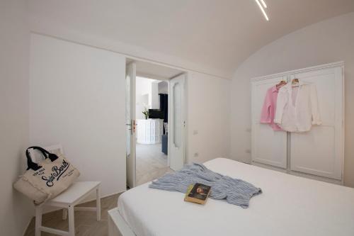 a white bedroom with a bed and a chair at Amalfi Venere house -balcony & seaview in Amalfi