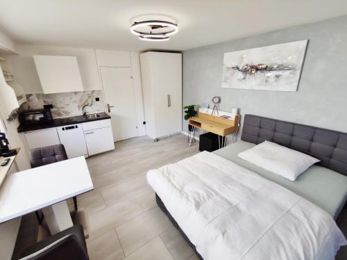 a bedroom with a bed and a desk and a kitchen at Business Style Apartment Ludwigshafen *Free Parking and WiFi* in Ludwigshafen am Rhein