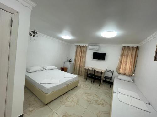 een slaapkamer met een bed, een bureau en een televisie bij Shaarei Zion in Oeman