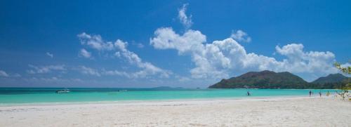 a beach with a group of people in the water at L'Hirondelle Self Catering Guest House in Anse Possession