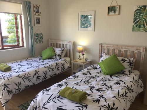 two beds in a room with green pillows at Waves Of Witsand in Witsand