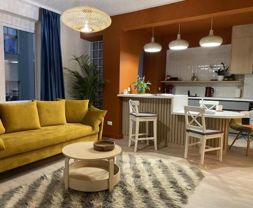 a living room with a yellow couch and a kitchen at JAY's Park Place in Cluj-Napoca