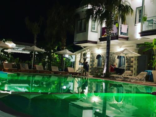 una persona de pie junto a una piscina por la noche en Hotel Sarajet e Pashait 1, en Dhërmi