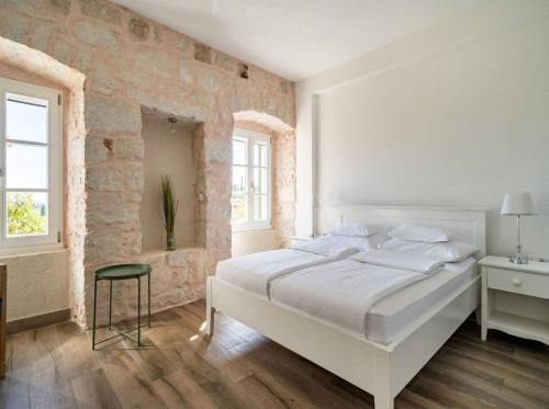 a bedroom with a white bed and a brick wall at Villa Joe in Čilipi