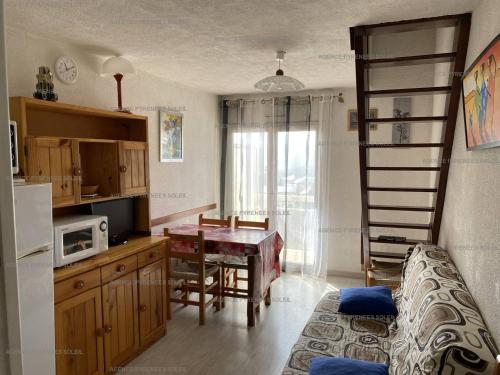 Cette chambre dispose d'une cuisine avec une table et une échelle. dans l'établissement Appartement T3 avec 5 couchages et balcon aux Angles - FR-1-295-162, aux Angles