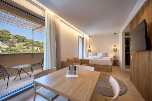 una habitación de hotel con una cama y una mesa y una habitación en TALAIA PLAZA ECORESORT BEGUR, en Begur