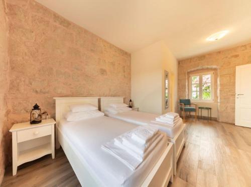 two white beds in a room with wooden floors at Villa Joe in Čilipi