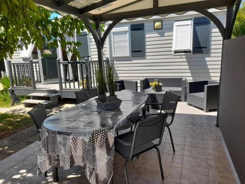 un patio avec une table et des chaises sous une pergola dans l'établissement Mobil'home à Dolus-d'Oléron (17) avec terrasse, cuisine d'été et proche plages - 4 couchages - FR-1-246A-120, à Dolus-d'Oléron
