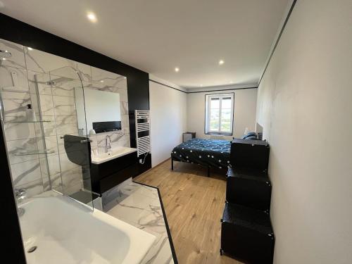 a bathroom with a tub and a sink and a bed at Le Champ Du Possible in Uxeau