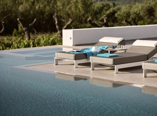 una piscina con due sedie a sdraio e un tavolo di Drallos Luxury Villa ad Alikanás