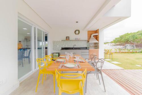 a dining room with a table and yellow chairs at SA06 Excelente Casa 5 Suítes - Reserva de Sauípe in Costa do Sauipe