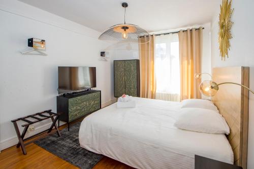 a bedroom with a large white bed and a television at Suites Mana - Le Manaloft, Chic et moderne avec salle privée de Fitness en plein centre-ville de Rethel in Rethel