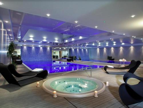 a hotel lobby with a swimming pool with chairs and a tub at Elite Apartments Waterlane SPA in Gdańsk